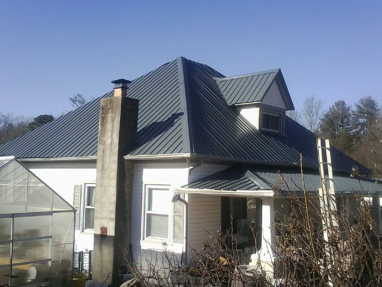 Dark blue standing seam metal roof on a white farmhouse with dormer — Slate & Tile Roof Repair by Roofing Brothers in Romeoville