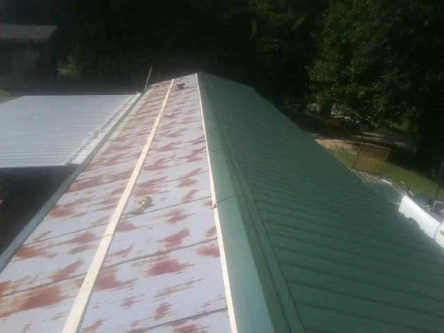 Old rusted panels beside newly installed green metal roofing — Wind Damage Roof Repair by Roofing Brothers in Romeoville