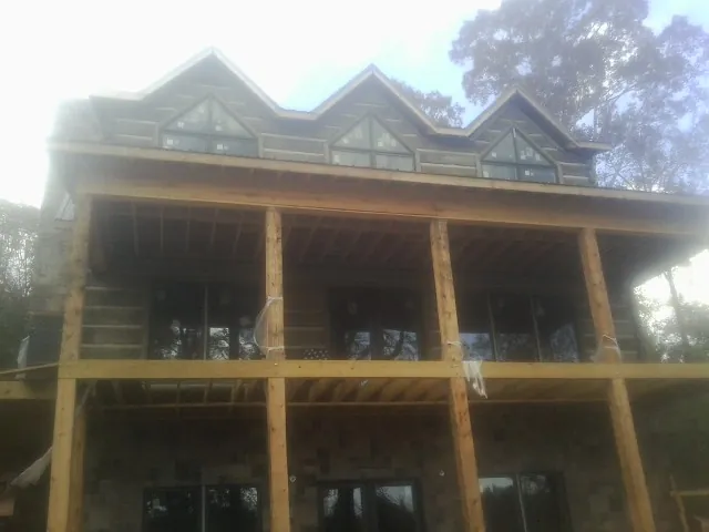 Dormers and porch framing on a large log home under construction — Roof Coating work by our crew in Romeoville