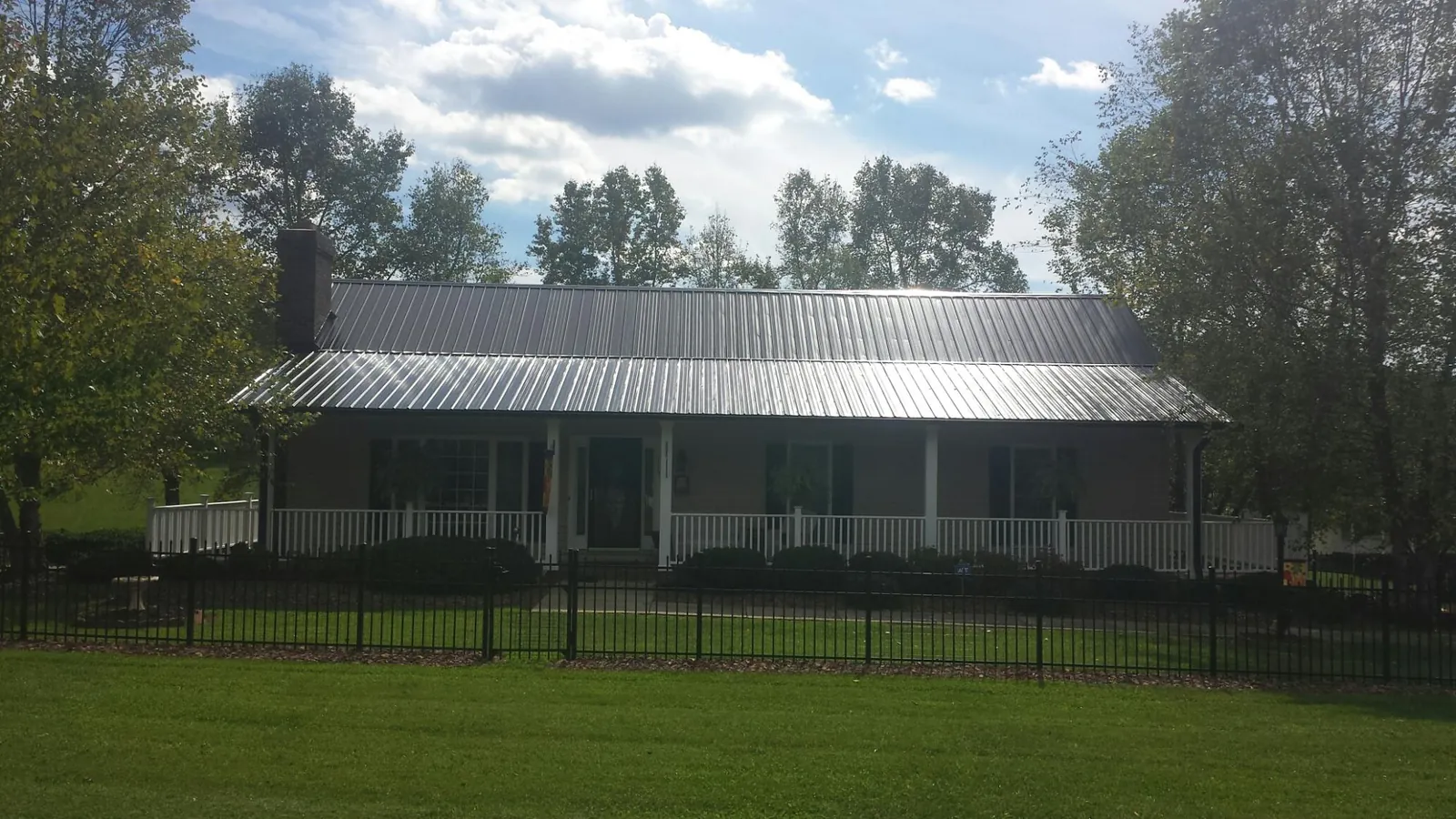 Gray metal roof on a brick ranch with a full width front porch — Gutter Guard Installation work by our crew in Romeoville