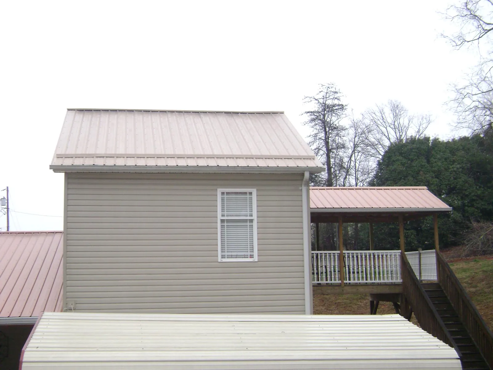 Tan metal roofs on a two story addition and attached porch, from a Roof Replacement job in Romeoville