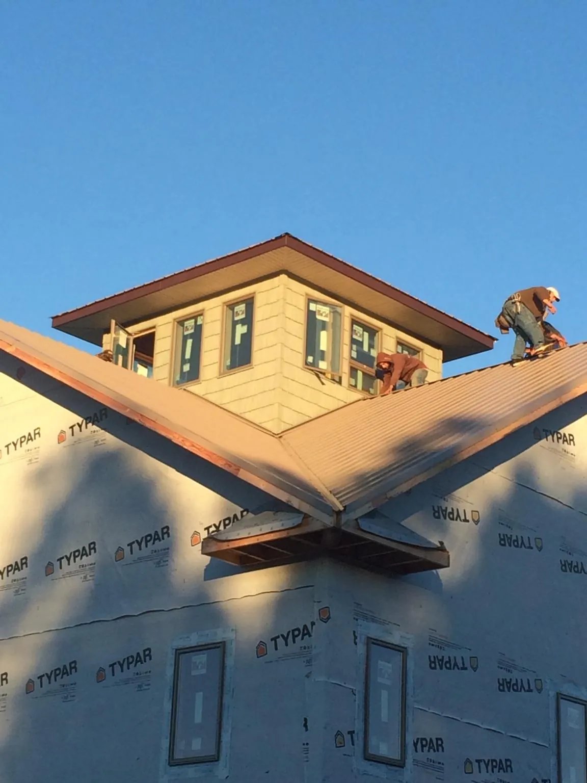 Roofers working around a rooftop cupola on a new metal roof at sunset — Roof Waterproofing in Romeoville by Roofing Brothers